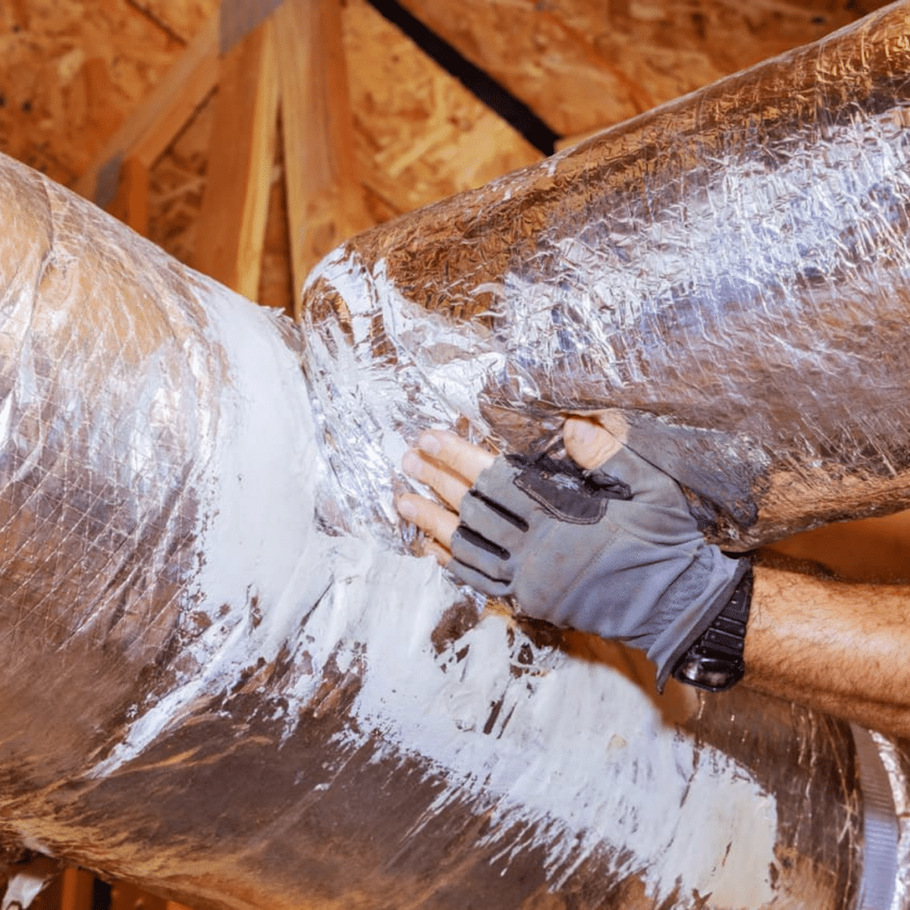 A technician sealing air ducts with protective tape to improve efficiency and prevent leaks