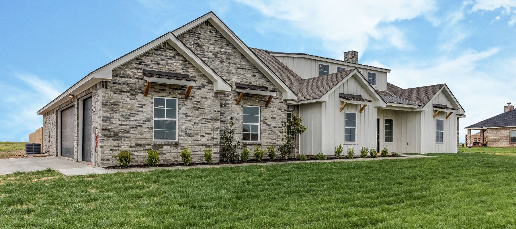Modern single-family home with a brick and siding exterior and manicured lawn