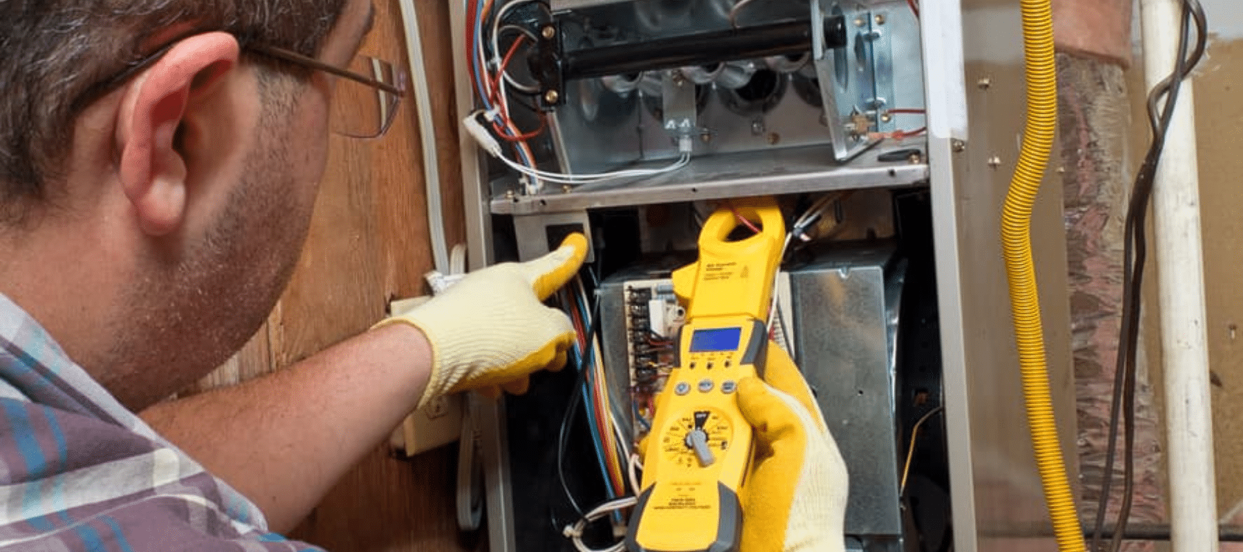 A technician examines the internal components of a furnace using diagnostic tools