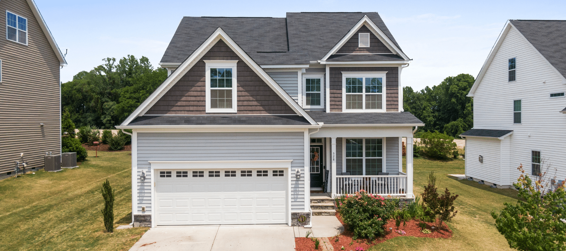 Modern two-story suburban home with gray siding and a white garage door